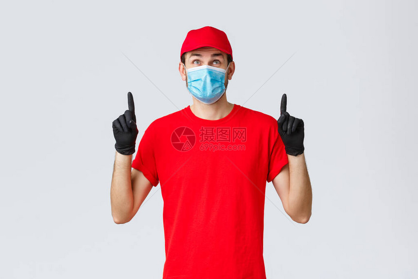 微笑的送货员红色制服帽和T恤戴橡皮手套的医疗面具图片
