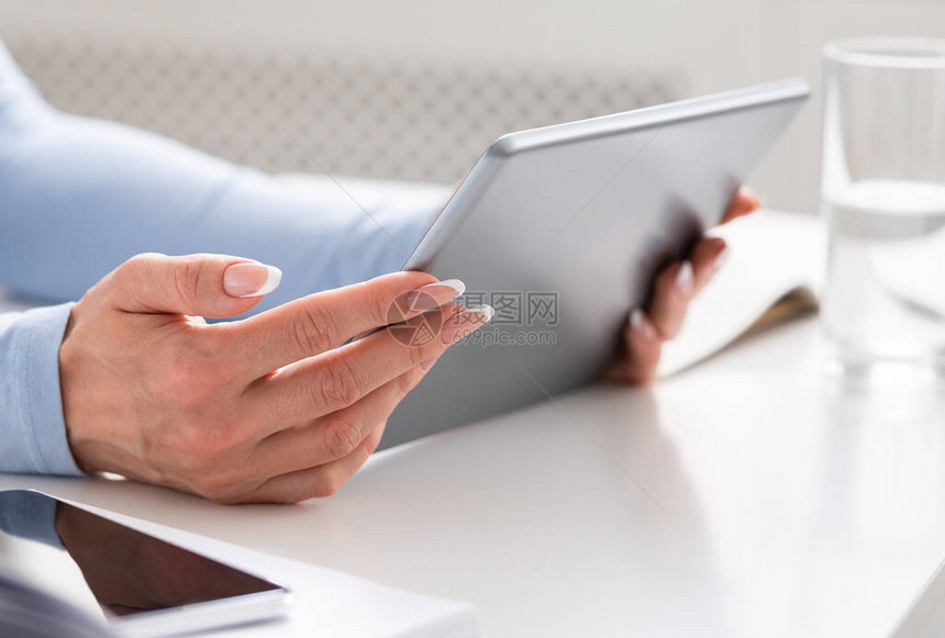 妇女双手将平板电脑放在白桌上用数字设备图片