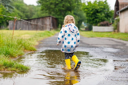 蹒跚学步的小女孩穿着黄色雨靴图片