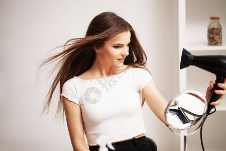 美丽的头发美丽的女孩使用吹风机图片