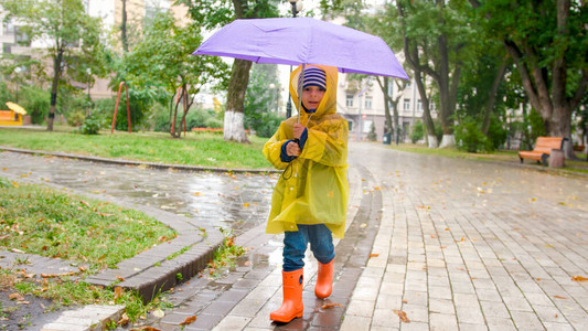 穿着雨衣的小可爱男孩的肖像拿着雨图片
