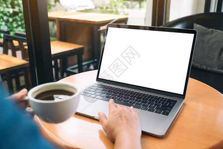 手在喝咖啡时使用和触碰用空白桌面屏幕的笔记本电脑触摸图片