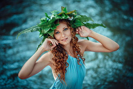 一位美丽的年轻女子红发和花圈在森林中献出鲜花和肥料庆祝图片