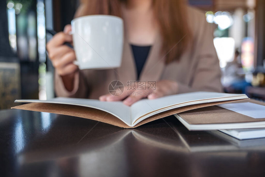 一位女在咖啡馆喝咖啡时阅读和开图片