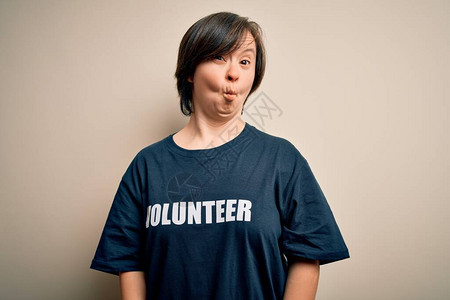 身穿社会护理慈善T恤的年轻综合症志愿者妇女用嘴唇疯狂和滑稽手势图片