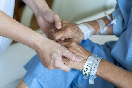 老年患者在床上与老年医生手牵进行信任和护理保健医疗护理人员和图片