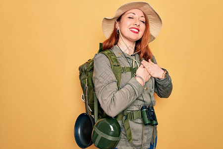 年轻的红发背包客女人徒步旅行时背着包和帽子图片