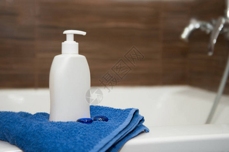 浴室里有一瓶白肥皂洗发水和蓝色毛巾复制空间图片