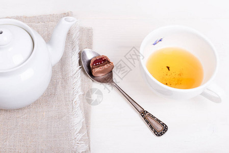 餐巾纸上的茶壶喝醉的日本绿花茶的杯子和带糖果的勺子图片