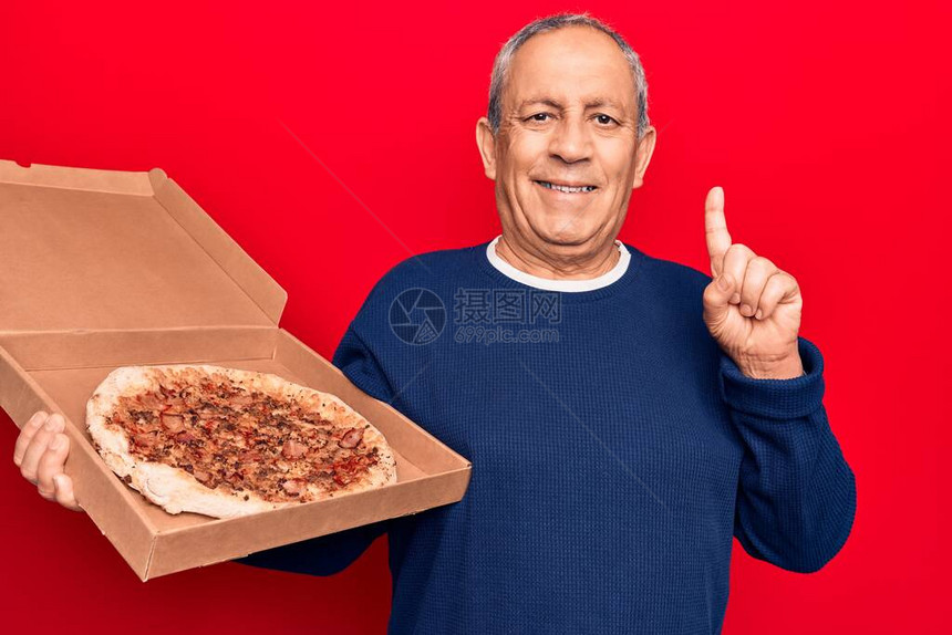 头发灰白的老人拿着意大利比萨饼的送货纸板图片