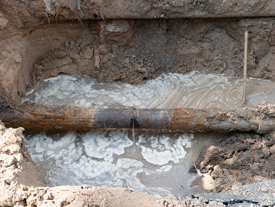 造成污水泄漏流和污染的破裂下水道生锈管道的特写镜头城市建筑工地的旧图片