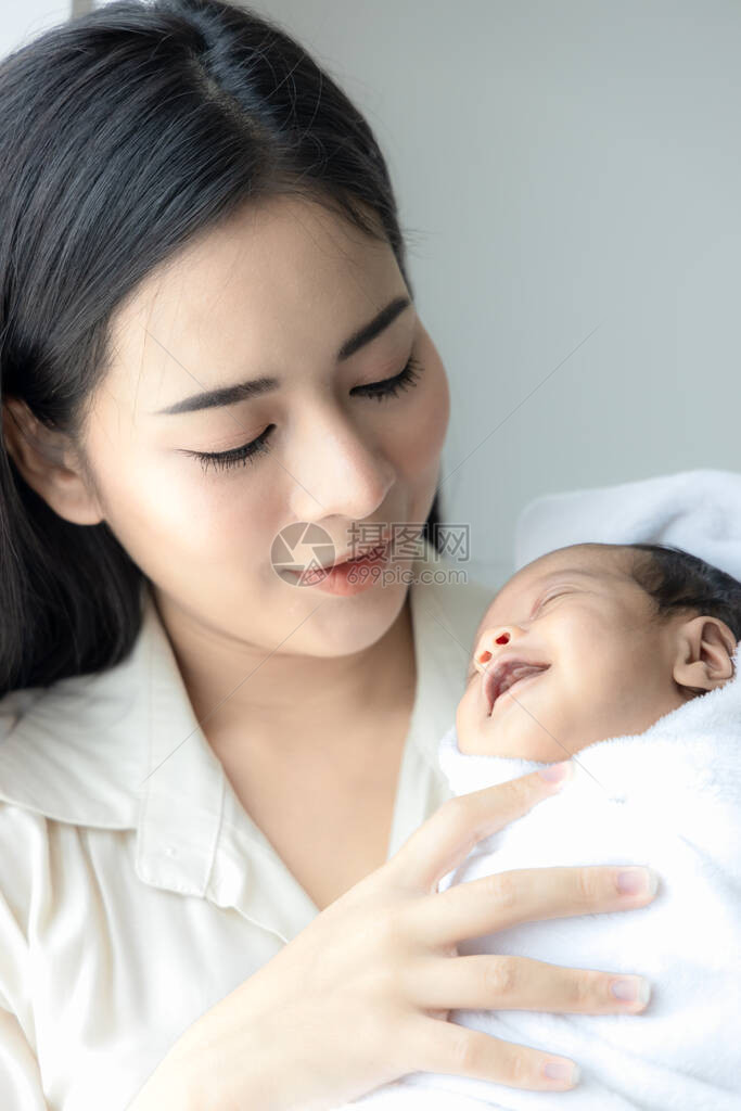 年轻亚洲母亲的肖像快乐地拥抱着她可爱的新生婴儿图片