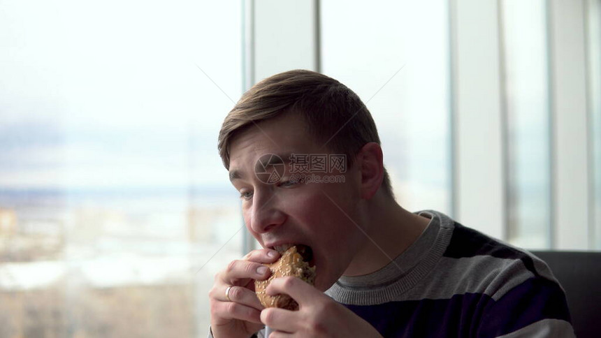 一个年轻人正在吃汉堡图片