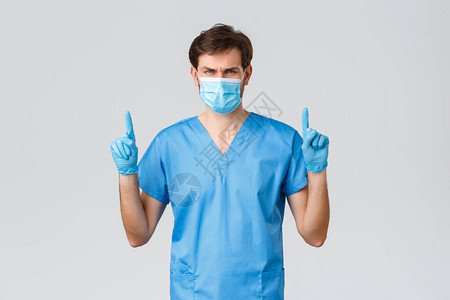 穿着蓝色磨砂医用面具和手套的严肃男医生图片