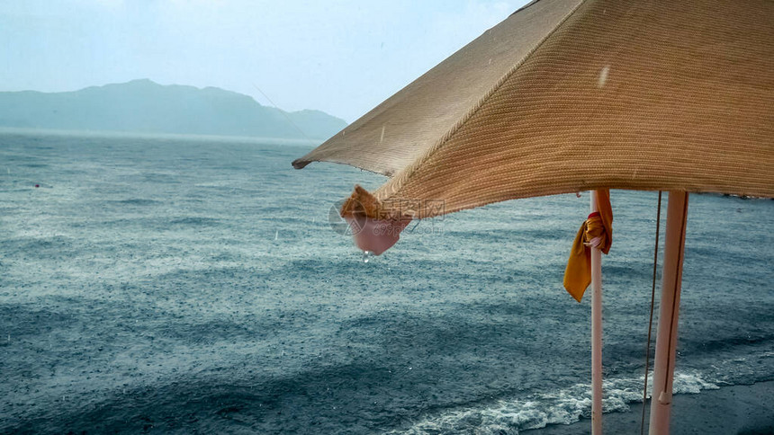 雨滴从沙滩上湿漉的太阳伞上落下图片
