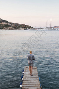 美丽的女人穿着豪华的夏装站在木码头上图片