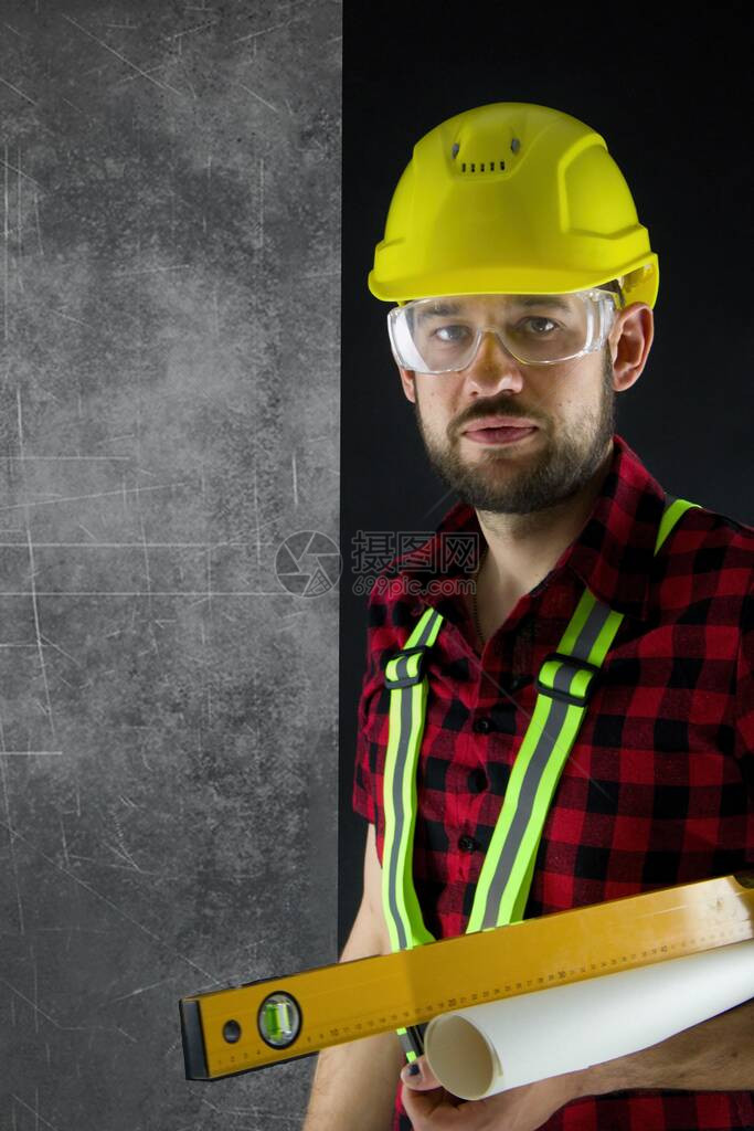 建筑工人站在墙边带黄色防撞头盔的建筑工人持有水平图片