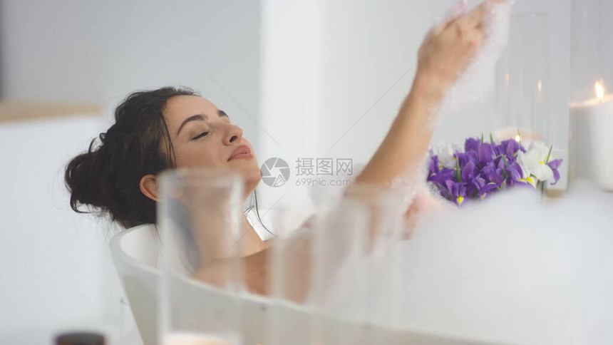 特写微笑女人用慢动作泡沫洗手放松的女孩在豪华酒店的泡浴中休息感的女人图片