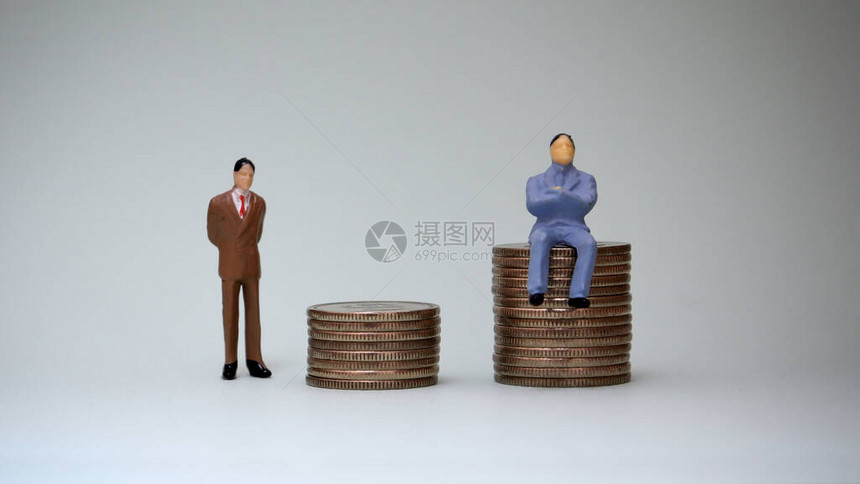 一个微型人坐在一堆硬币中一个微型人站在图片