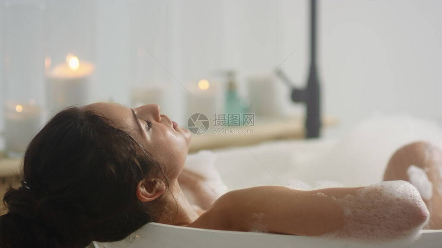 特写放松的女人躺在浴室的浴缸泡沫中浪漫的女孩在家里的浴缸里放松关闭了在室内洗图片