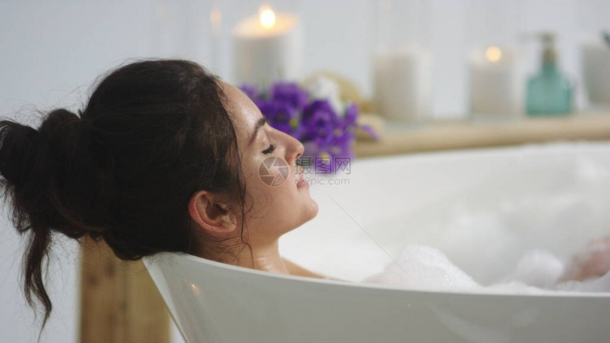 特写放松的女人在慢动作中吹泡沫感女孩在家里洗澡时洗手的侧面图平静的女人在浴缸里休息图片