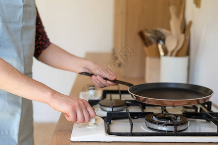 妇女用煤气炉灶和锅子烹饪食品的作物透视图片