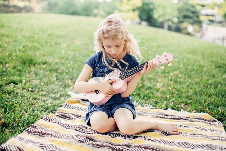 可爱的金发女孩在户外玩粉红色的吉他玩具孩子在公园里演奏音乐和唱歌孩子们的爱好活动温柔难忘的真实坦图片