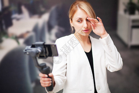 年轻商业女在公司办公室录制智能手机视频博客Smart图片