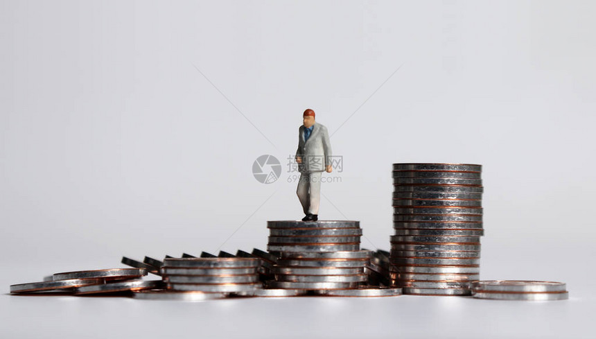 一个微型老人在一堆硬币上行走图片