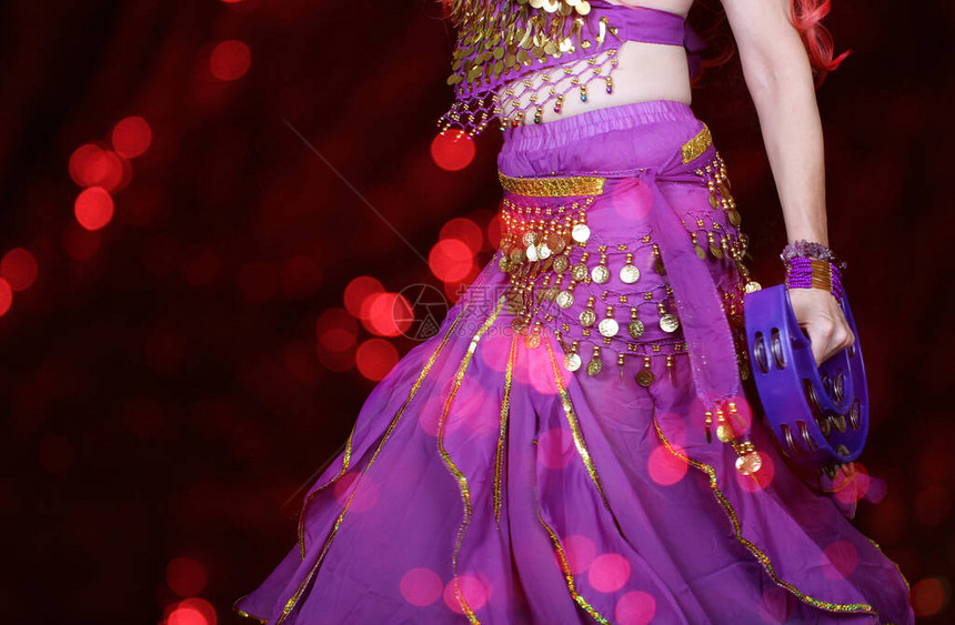 肚皮舞者特写穿着紫色与红色散景背图片