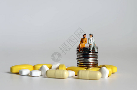 一对老微型夫妇和药丸坐在一堆硬币上老龄化社会对老年人医疗保图片