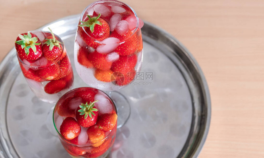 白背景和热带树叶上有玻璃的冰丝草莓冷饮图片