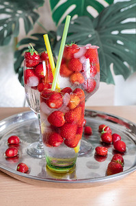 白背景和热带树叶上有玻璃的冰丝草莓冷饮背景图片