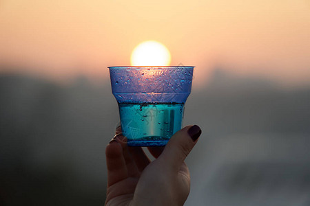 女人用手握着玻璃挡住太阳下山在城市风景背中与模高清图片