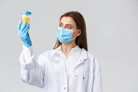临床实验室的专业医生擦洗和医用口罩查看尿样患者对冠状病图片