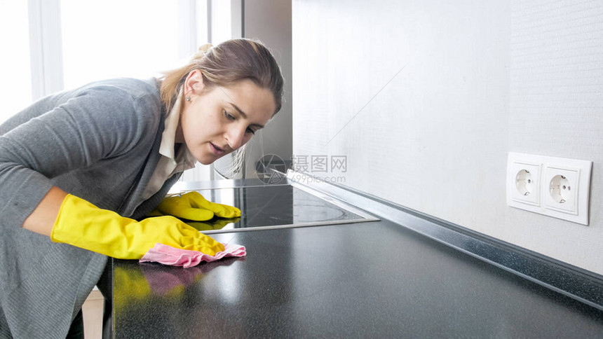 年轻女在做家务时清洗和打扫厨房表面和反图片