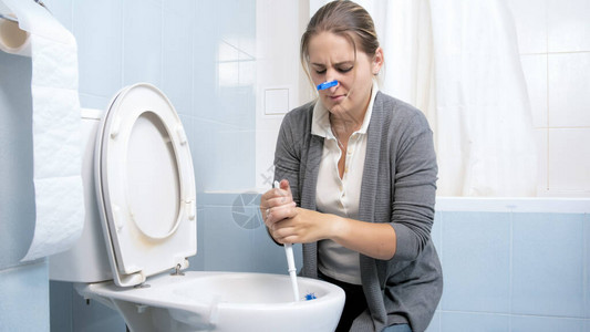 年轻女人洗脏厕所闭上鼻子图片