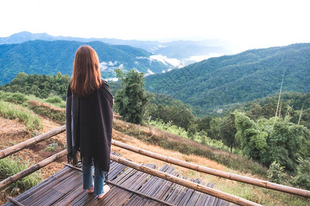 一个女人独自站在雾天看山早上蓝天背景图片