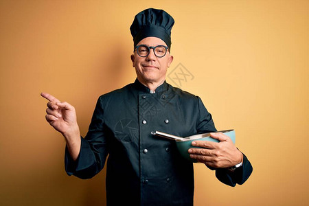 中年人英俊的灰头发厨师男身着烹饪制服戴帽子手图片