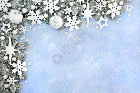 圣诞白雪覆盖的边界与柔和的蓝色背景上的白星雪花和球摆设装饰图片