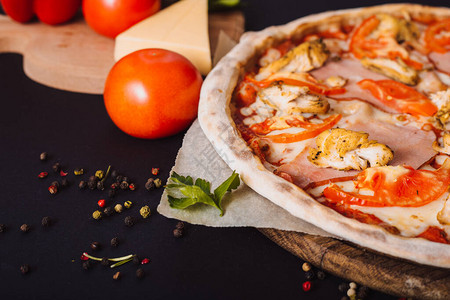黑混凝土背景的西红柿辣椒披萨和烹饪素材图片