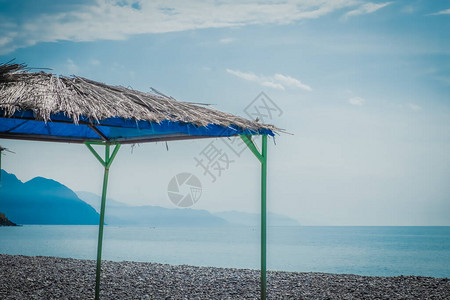 海滩区的视图以大海和山脉为背景的太阳伞空旷的海岸线晚图片