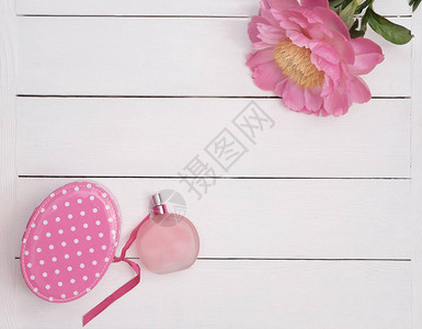 粉红色香水瓶和牡丹花白色木制背景上图片
