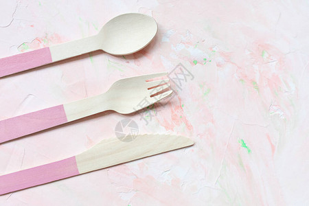 粉红色背景的一次环保木制餐具勺子刀叉餐具图片