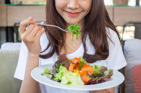 坐在店里的女孩开心地吃着沙拉保持健康图片