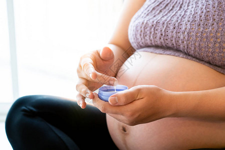 2432周的亚洲孕妇在腹部涂抹护肤乳液并轻按摩孕妇的放松和健康图片