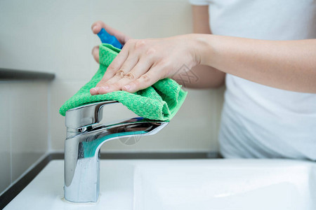 女管家在马桶的洗脸盆上清洗一个肮脏的不锈钢水龙头图片