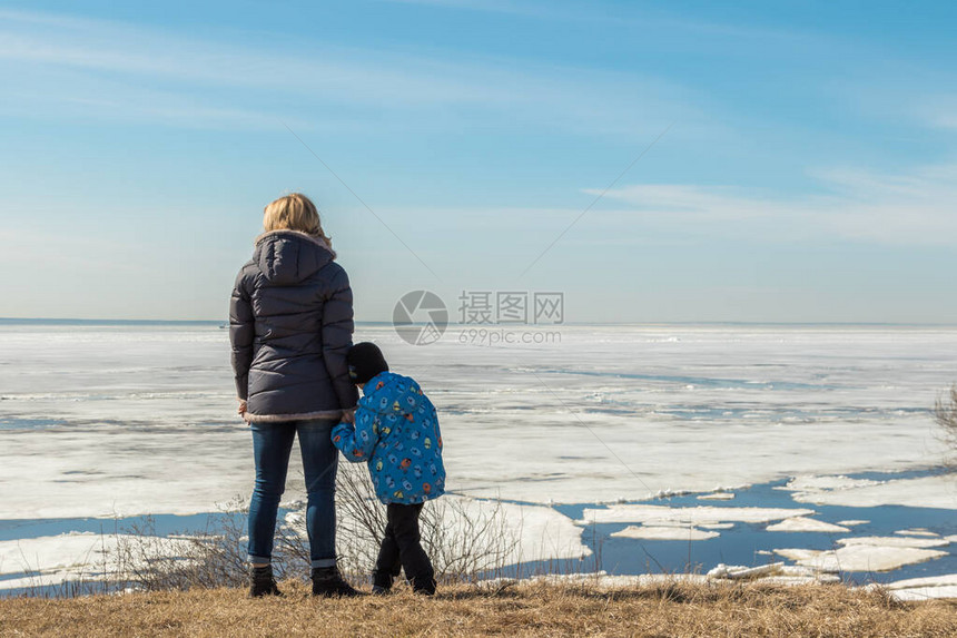 俄罗斯圣彼得堡一个带着一个小男孩的女人站在沙滩上看着白图片