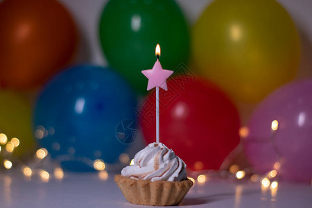 带有粉红星形蜡烛的蛋糕背景上有多色气球和灯光派对生日概念复制空间图片