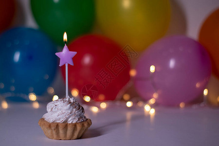 带有紫色星形蜡烛的蛋糕在背景上多色气球和灯光背景图片